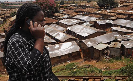 A woman speaks on a mobile phone in front of Kibera