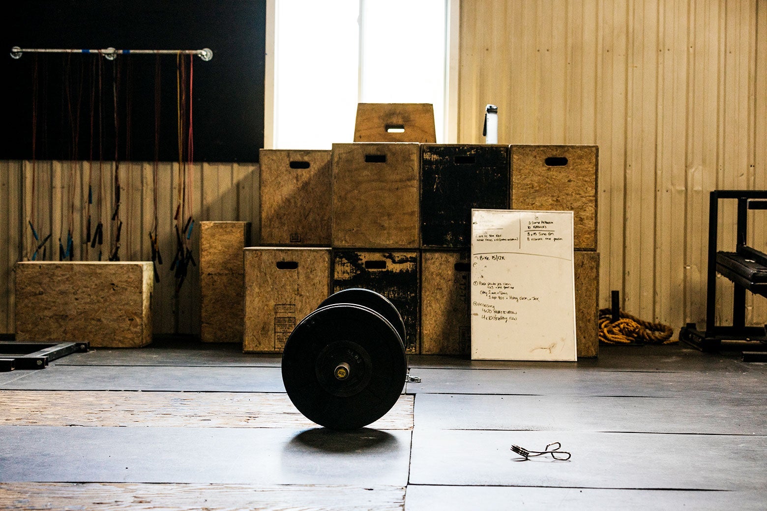 A barbell with weights on it sits in an empty gym.