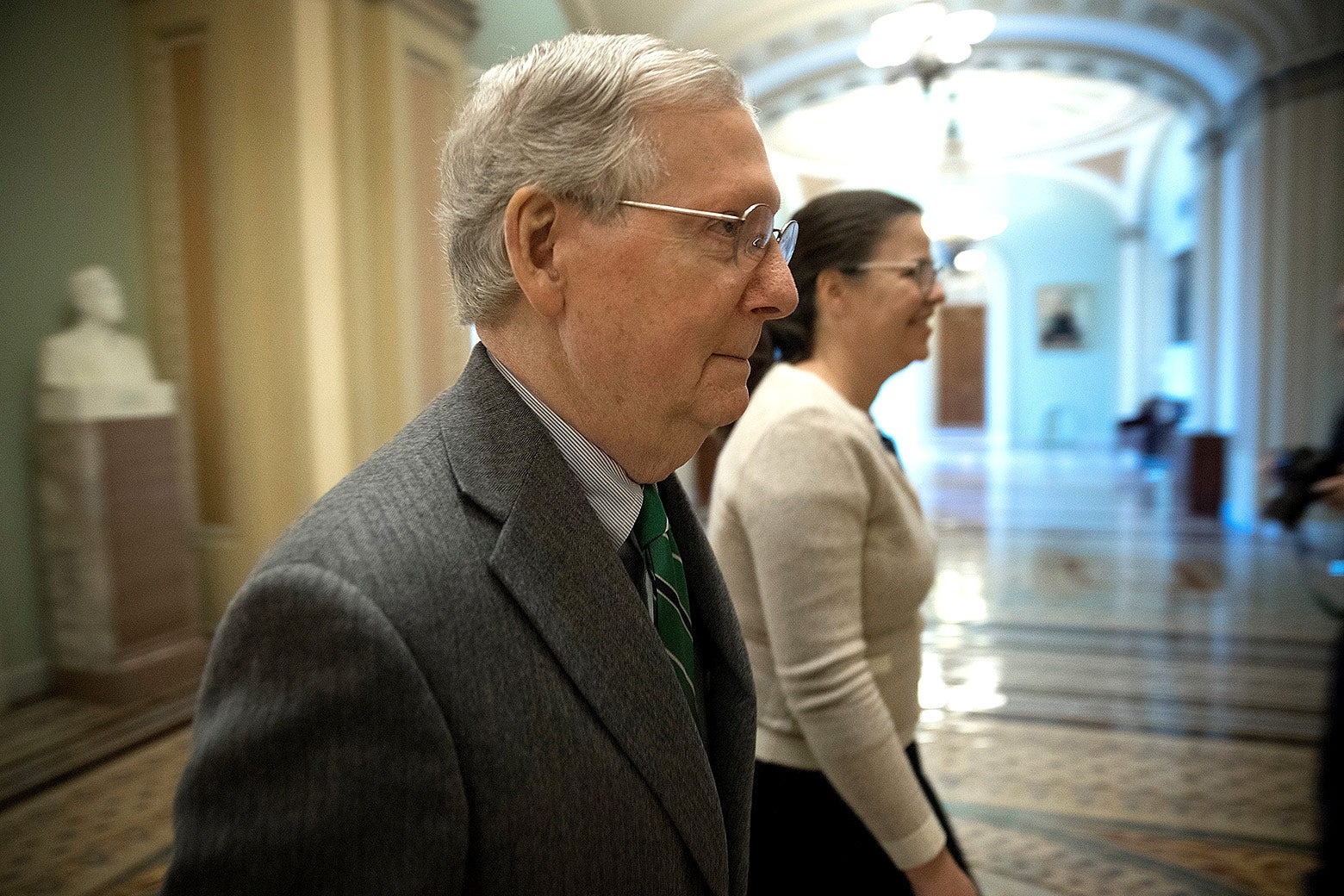Mitch McConnell and an unidentified woman walk through the Capitol.