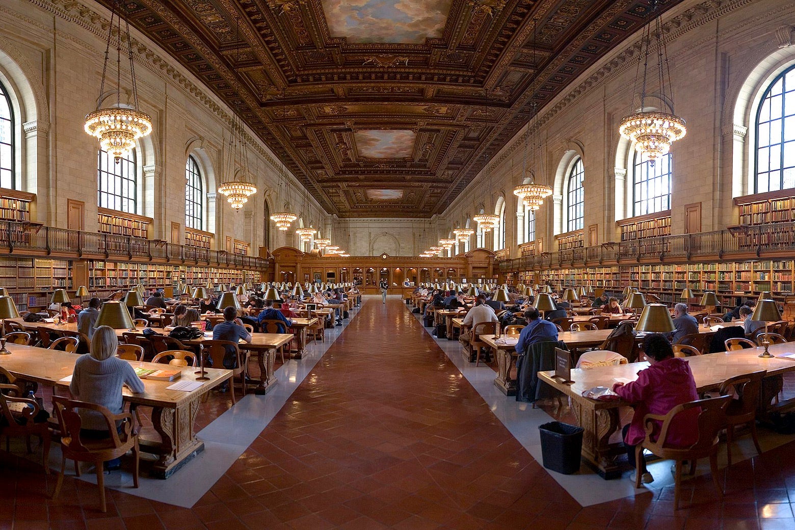 Patrons sit at long desks in an ornate reading room.