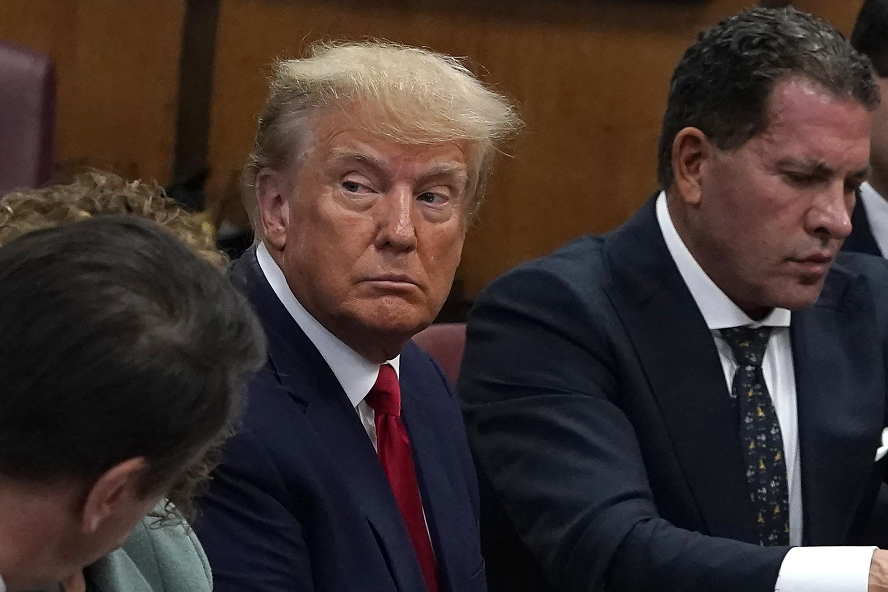 Donald Trump sits in a courtroom, surrounded by counsel