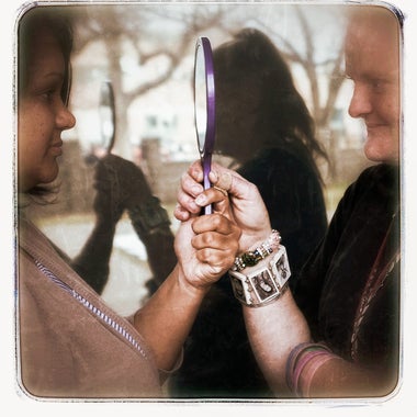 Two women hold a handheld mirror. This image appears in the book EXPOSURE: Homelessness through the lens of art & poetry.