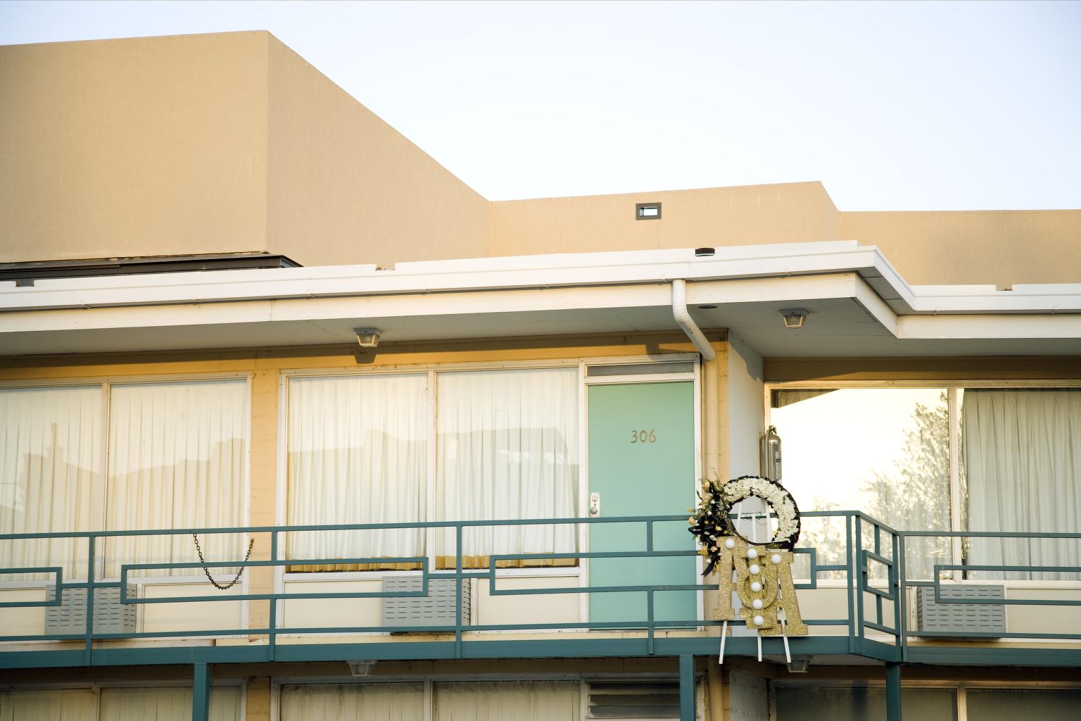 Exterior of a 1950s-era motel, with a commemorative wreath outside Room 306.