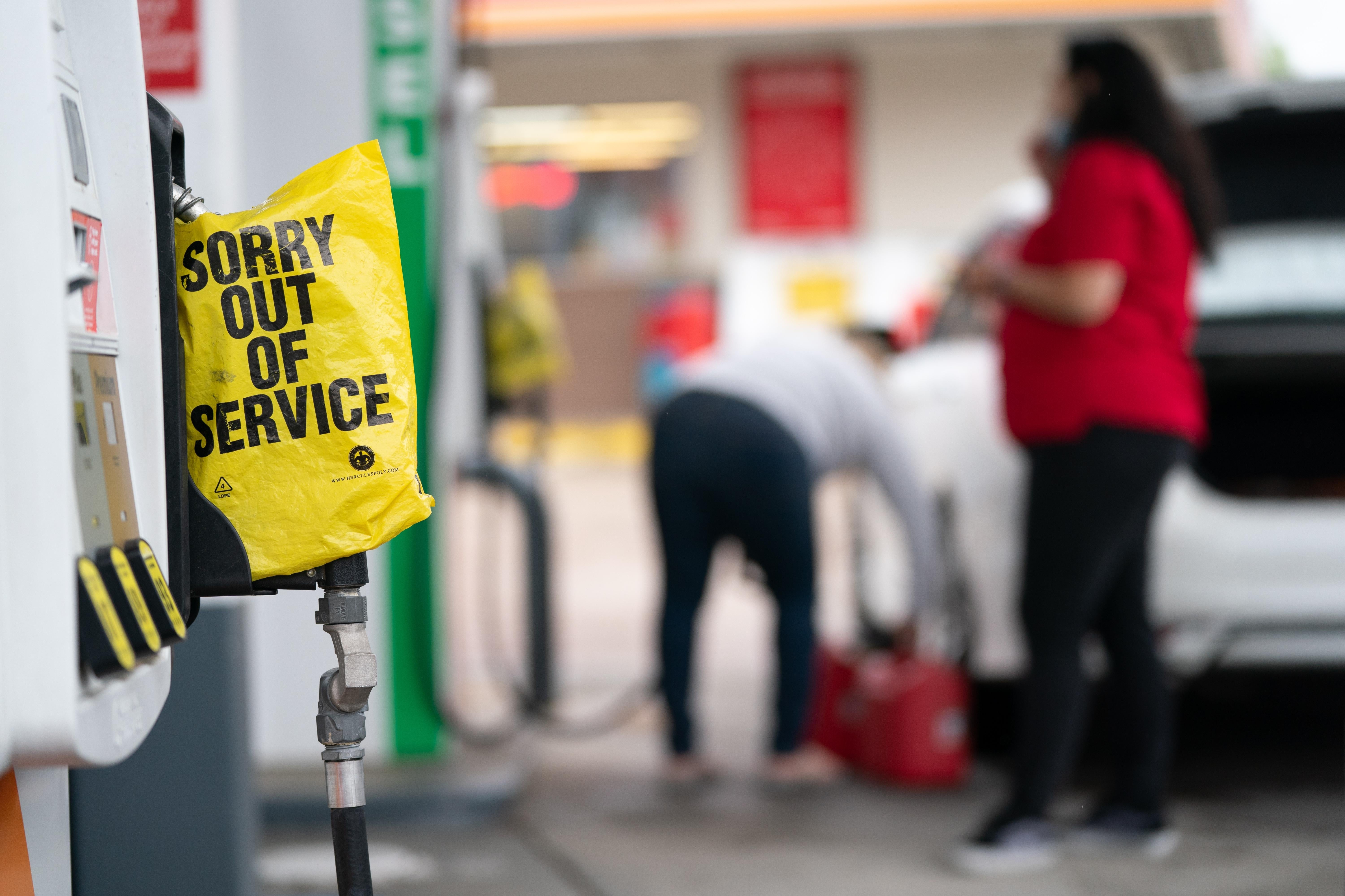 A yellow plastic "Sorry out of service" bag covers a gas pump handle.