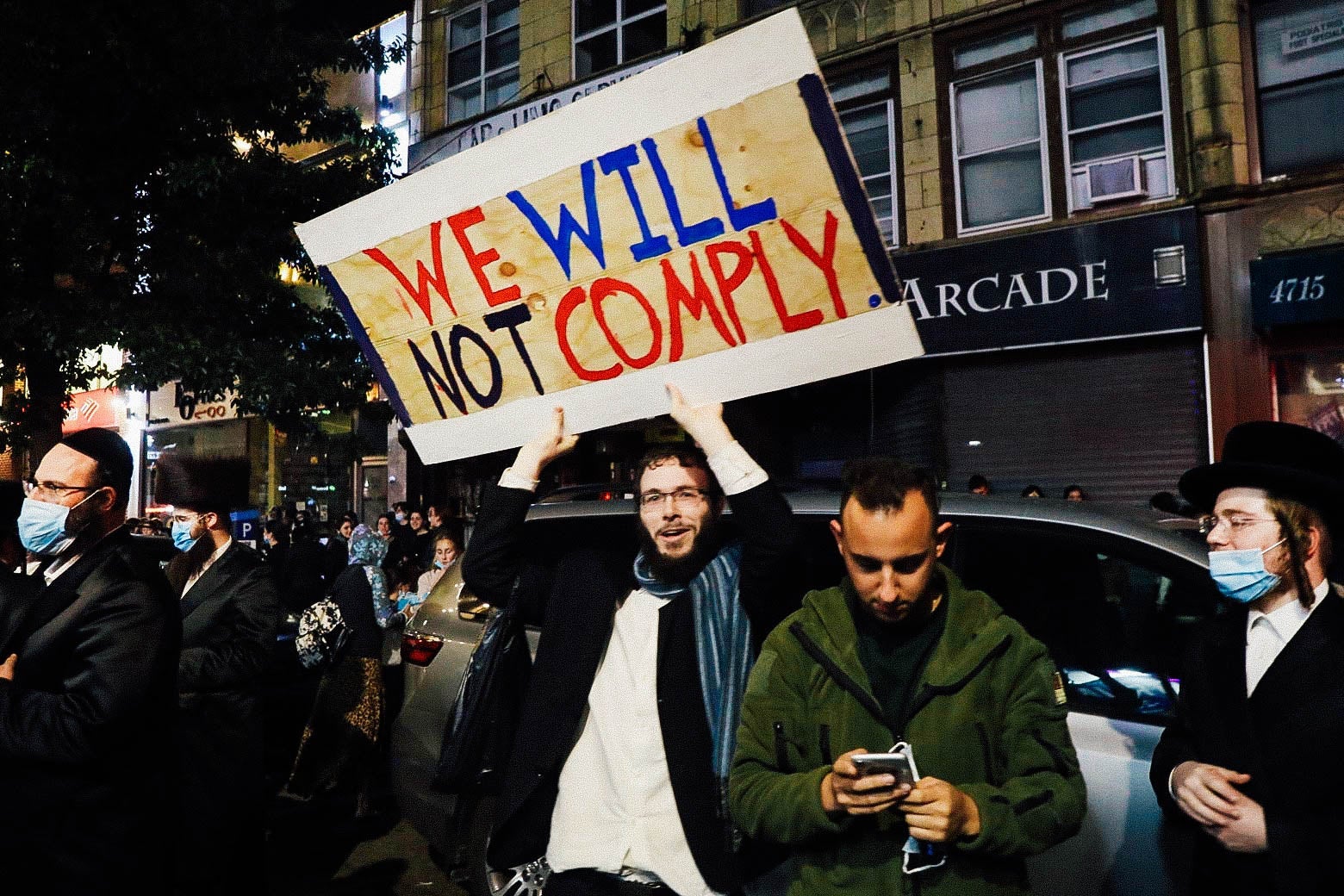 A man holds up a sign that says, "We will not comply."