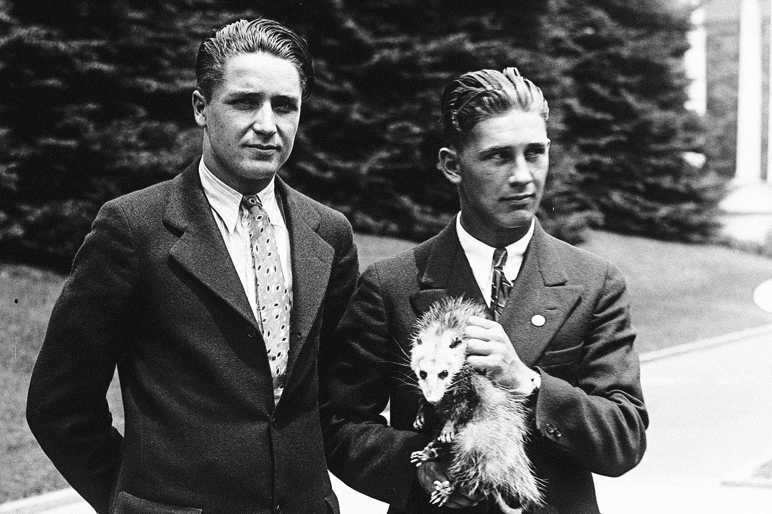 Two suspiciously old-looking “high school students” holding an angry possum in front of the White House.