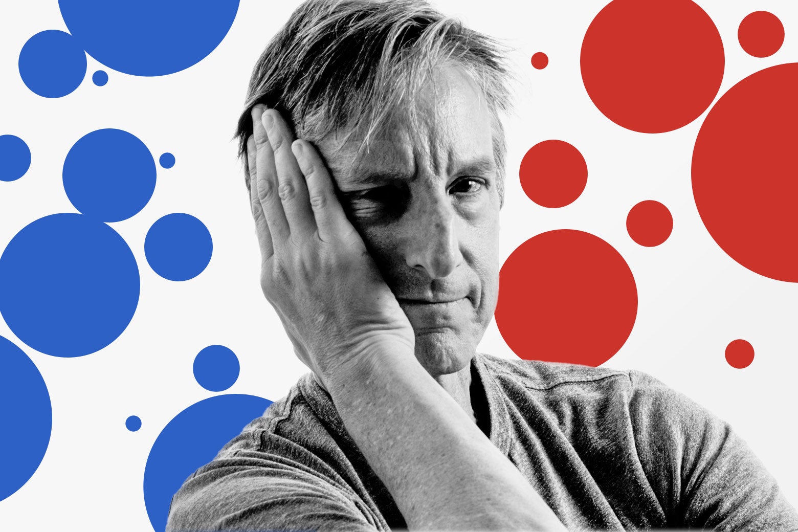 A white man puts his hand to his face against a backdrop of red and blue polka dots.