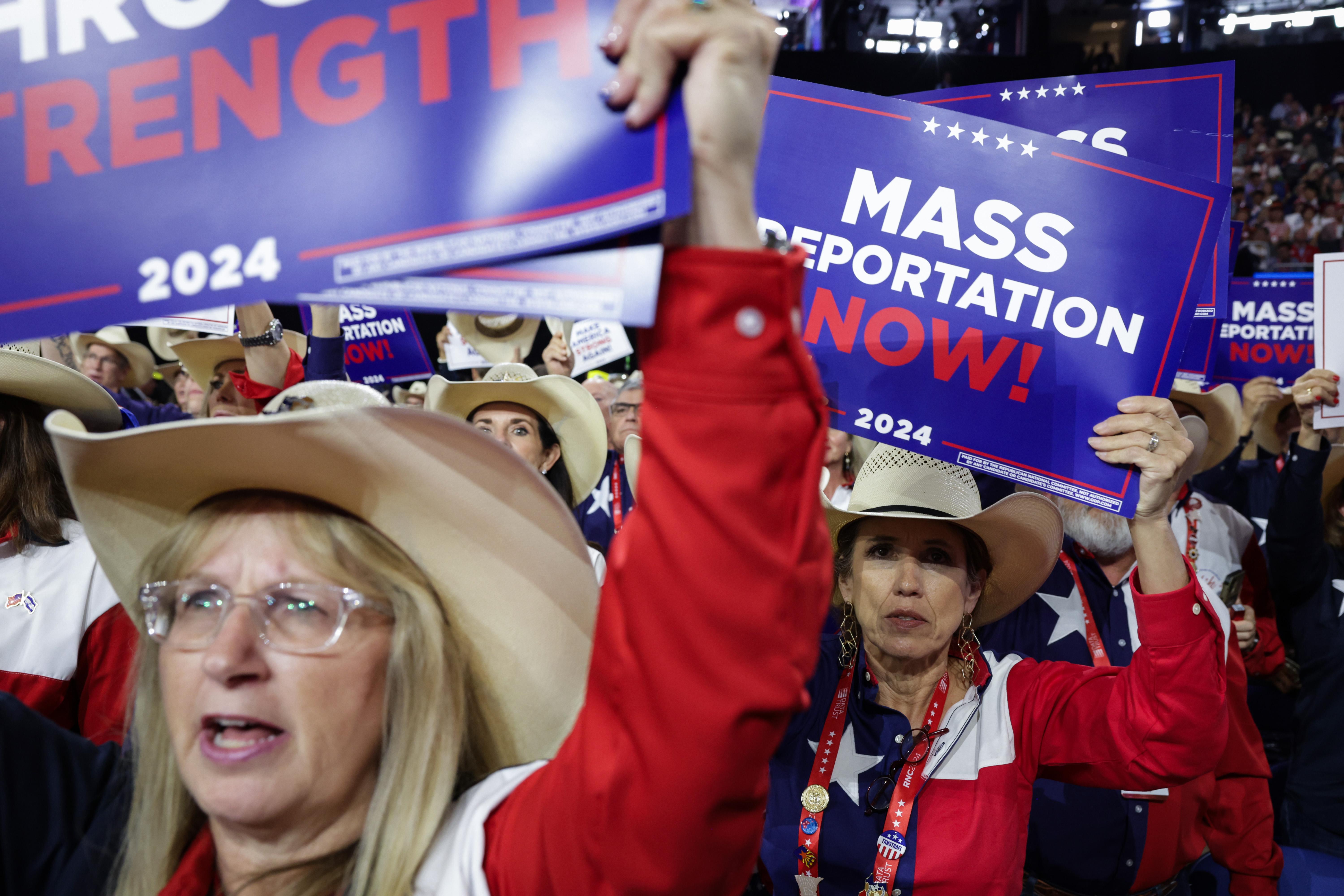 People hold Trump signs that read "Mass Deportation Now!"