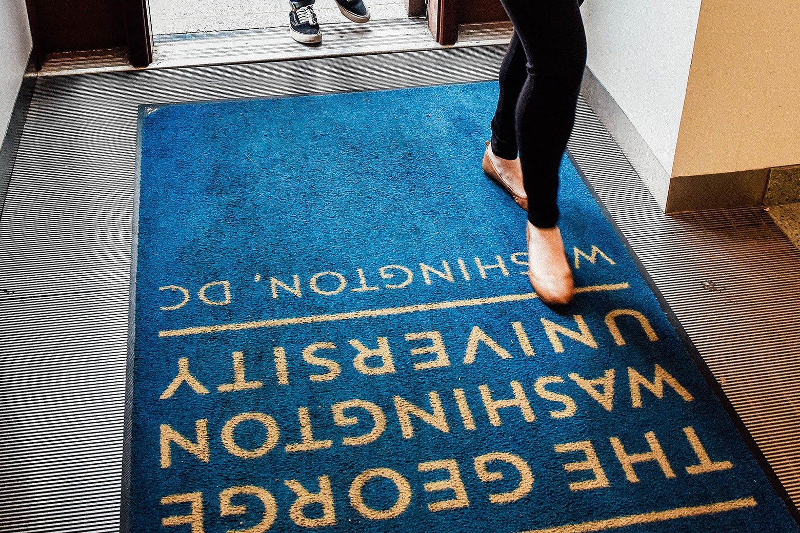 Admitted George Washington University students and their parents walk across a branded doormat as they tour the campus before deciding whether or not to enroll on April 26, 2017, in Washington.