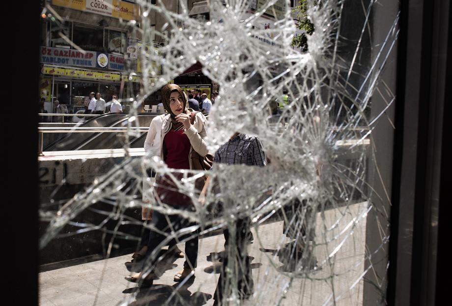 A woman looks at shattered windows as she walks past the entrance of a building damaged during previous day clashes between protesters and riot police, near the central Kizilay square in Ankara, on June 5, 2013. 