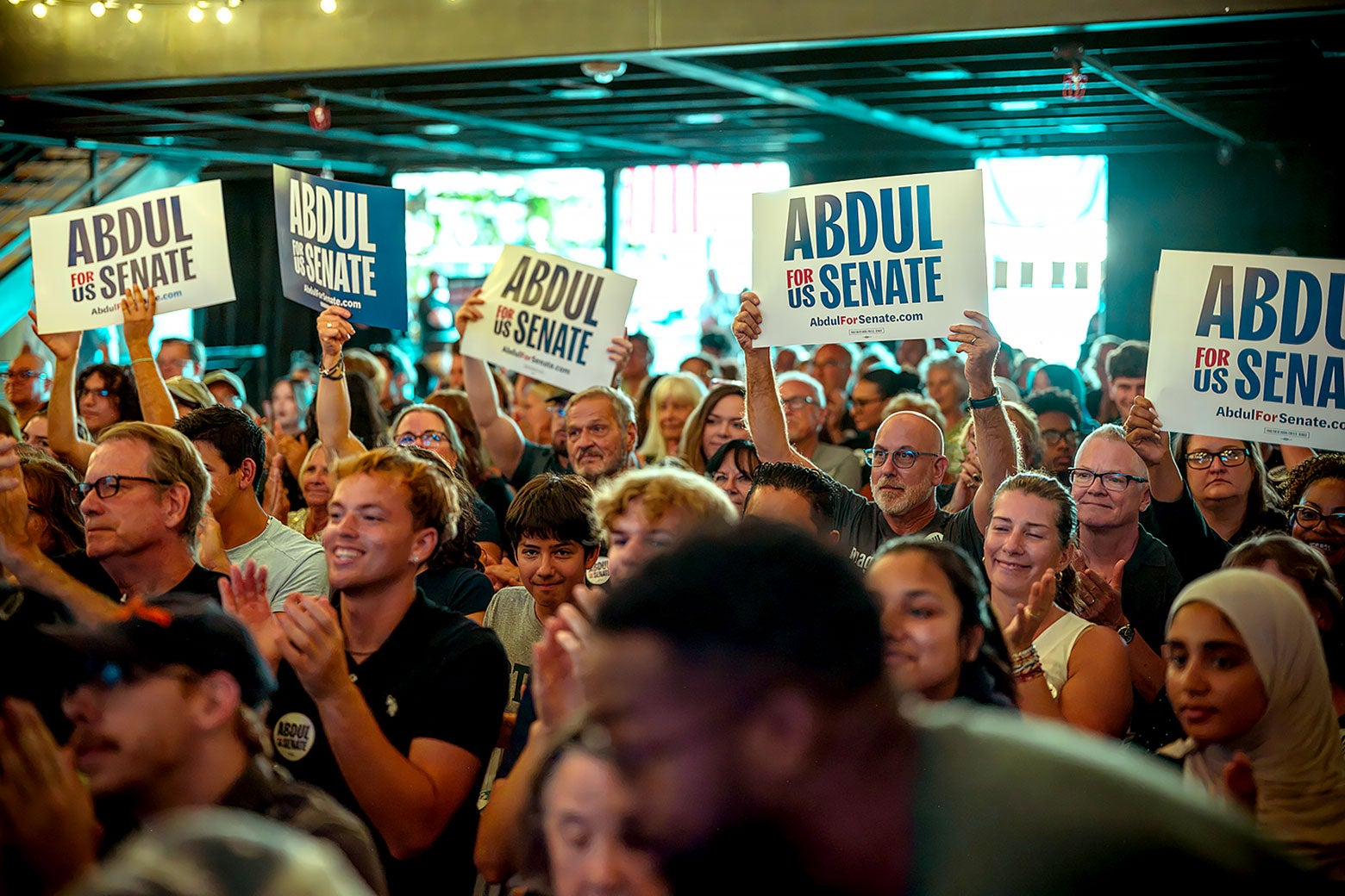 Crowd members at the MSU event hold up signs that say "Abdul for U.S. Senate."