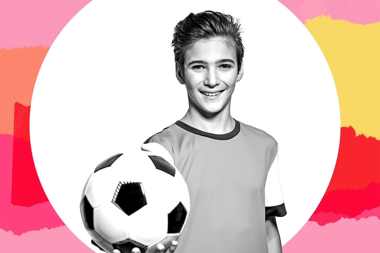A young boy in a soccer uniform holding out a soccer ball.