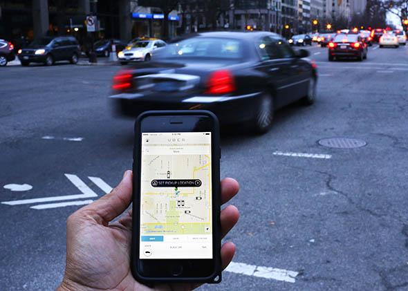 An Uber application is shown as cars drive by in Washington, DC on March 25, 2015. 