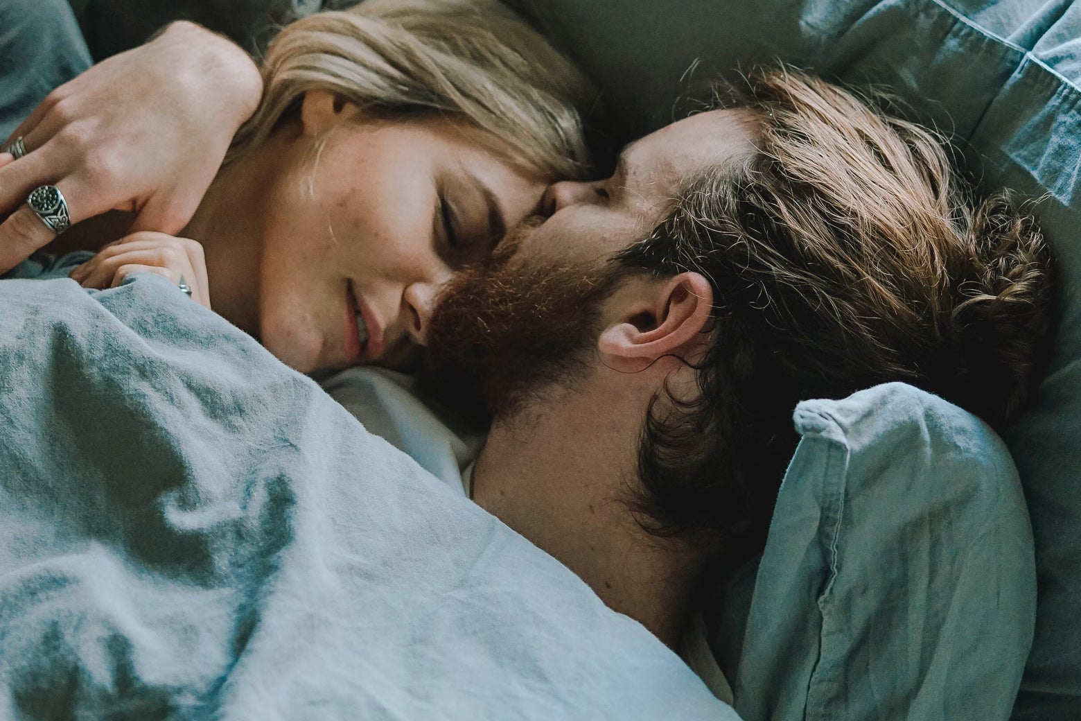 A man and a woman cuddling in bed.