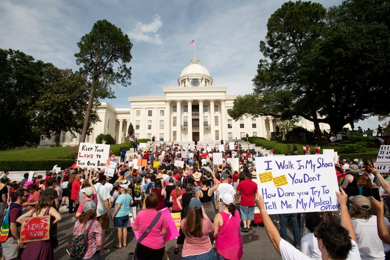 A crowd of demonstrators holding pro-life signs rallies in front of the Alabama state capitol.