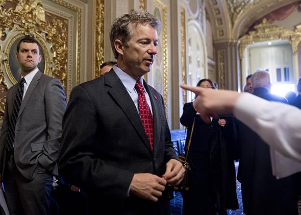 Republican Senator Rand Paul of Kentucky talks with a staff member as he walks to participate in a cloture vote.