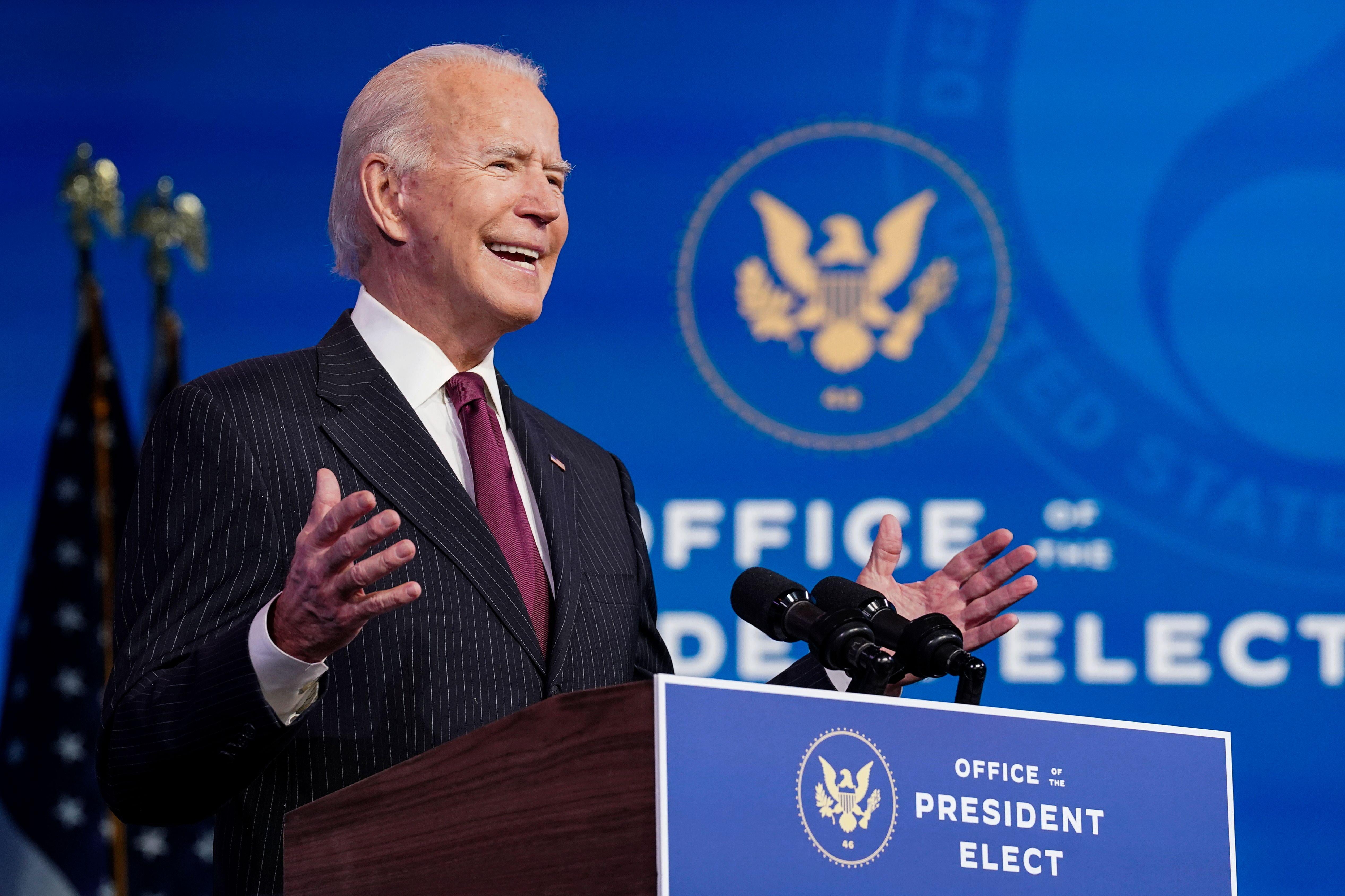 Biden speaks and gestures at a podium marked Office of the President Elect