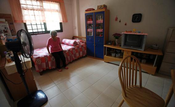 Emily Low, 78, sits on a bed in the combined living room and bedroom of her one-room Housing Development Board flat in Singapore November 2, 2007.