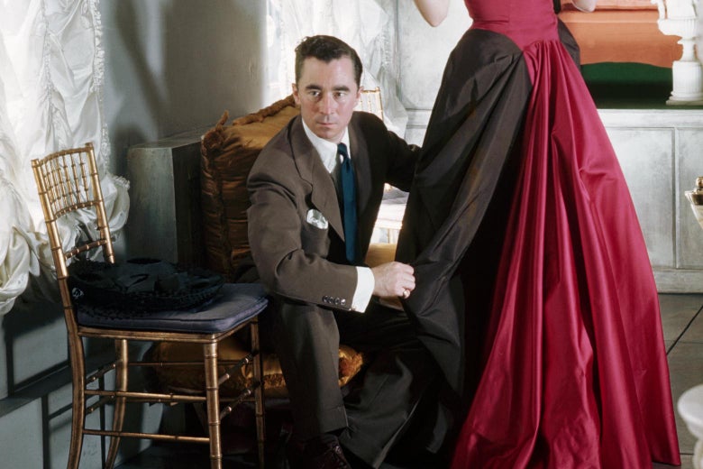 Charles James adjusts the drape on a woman’s gown.