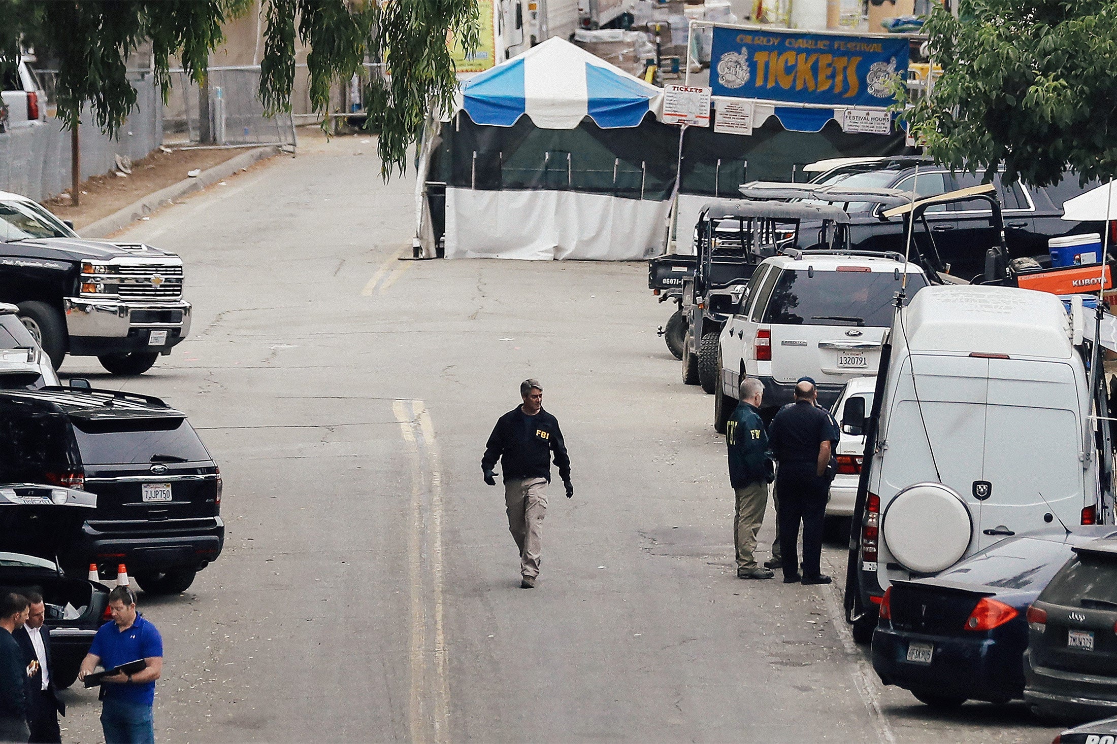 An FBI agent walks in the middle of a street near a ticketing booth for the Gilroy Garlic Festival.