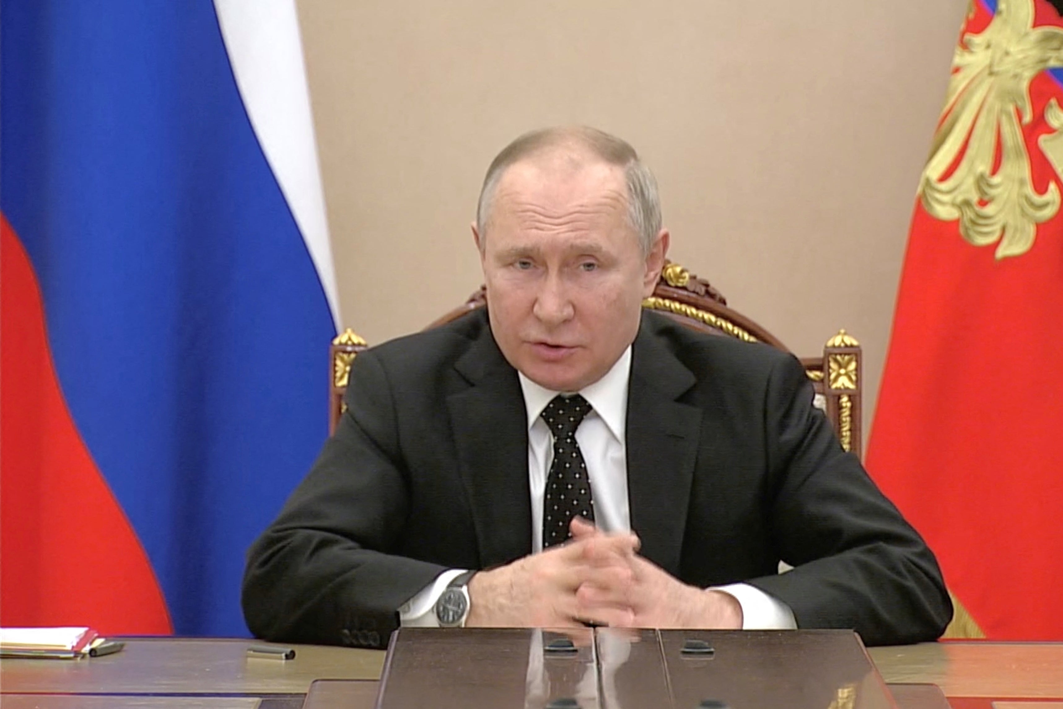 Putin speaks as he sits at a conference table