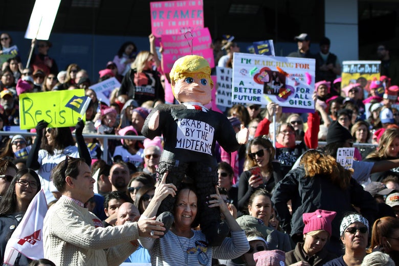 Participants, one with a US President Donald Trump figure, stand strong and applaud with their signs during the Women's March Anniversary 'Power To The Polls' event, January 21, 2018 at Sam Boyd Stadium in Las Vegas, Nevada.The rally is aimed at starting a national campaign to register voters, increase support for women and secure progressive seats in the upcoming midterm elections.