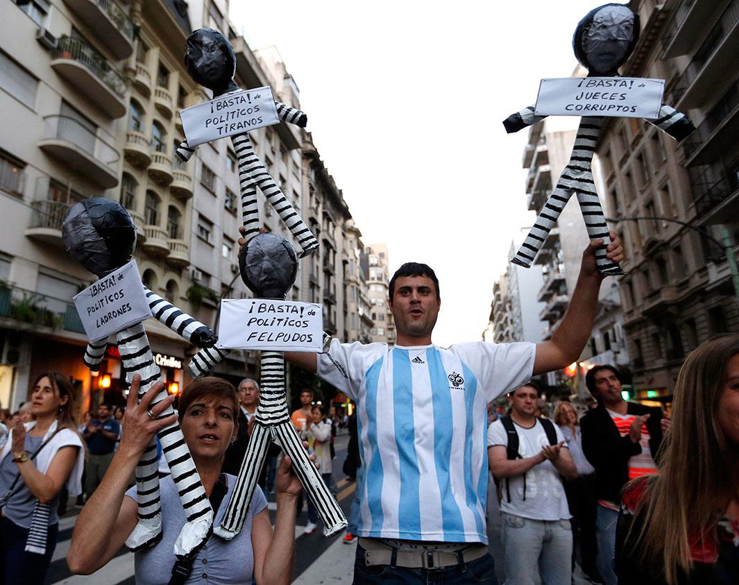 Protesters hold effigies representing judges and politicians dressed as inmates during an anti-government rally in Buenos Aires on Nov. 13, 2014. Diverse organizations rallied against inflation, corruption, and high crime rates in widespread demonstrations organized via social media networks. The signs under the effigies read: “Enough thieve politicians,” “Enough servile politicians,” “Enough dictator politicians,” and “Enough corrupt judges”
