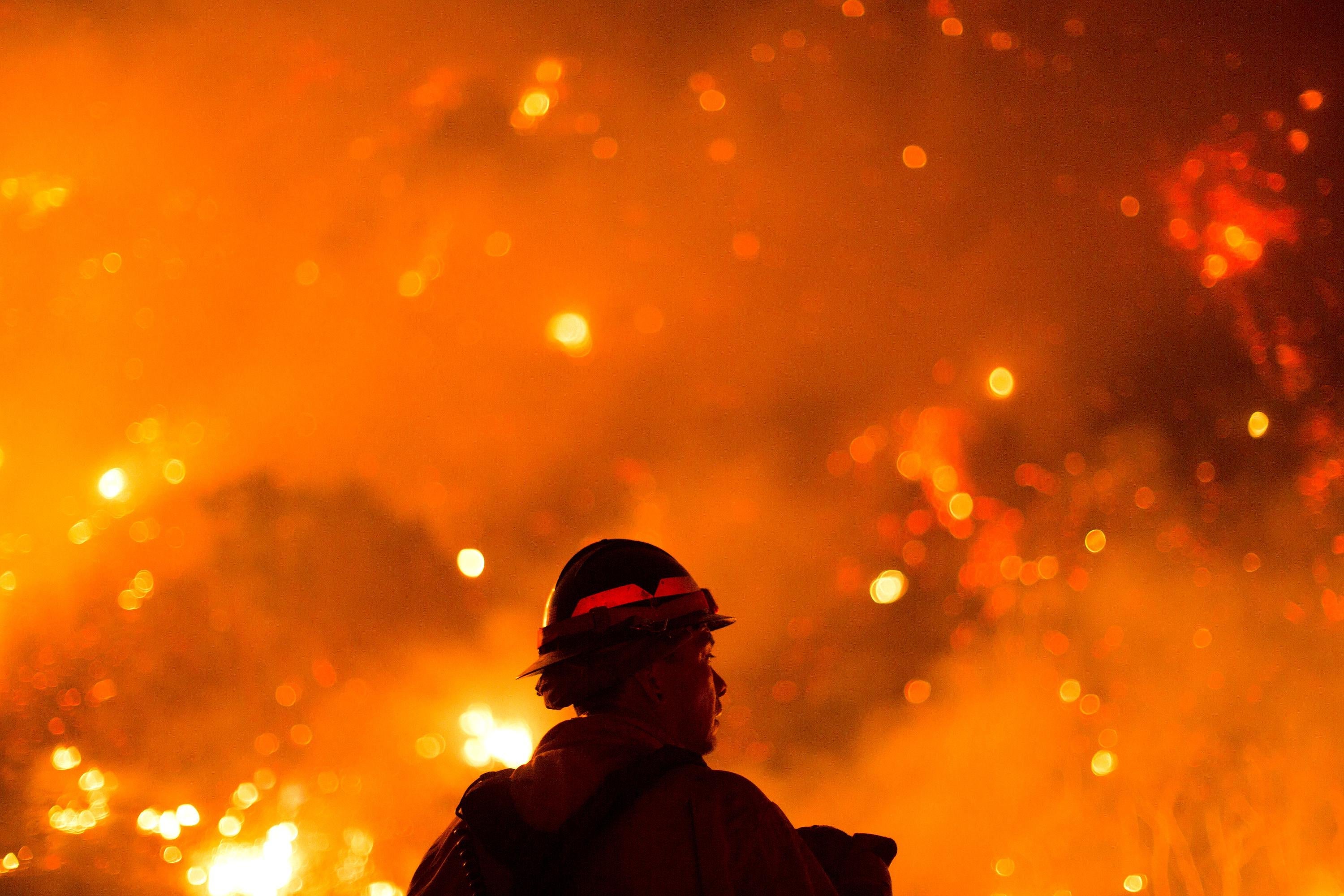 A firefighter looks at a wildfire.