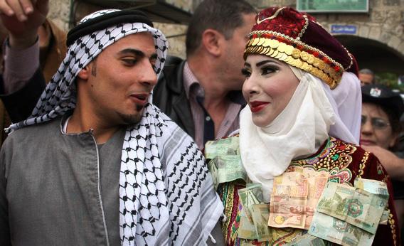 The Palestinian bride and groom Mhaha Salam, right, and Thayer Qasem, left, walk down the street on their wedding day.