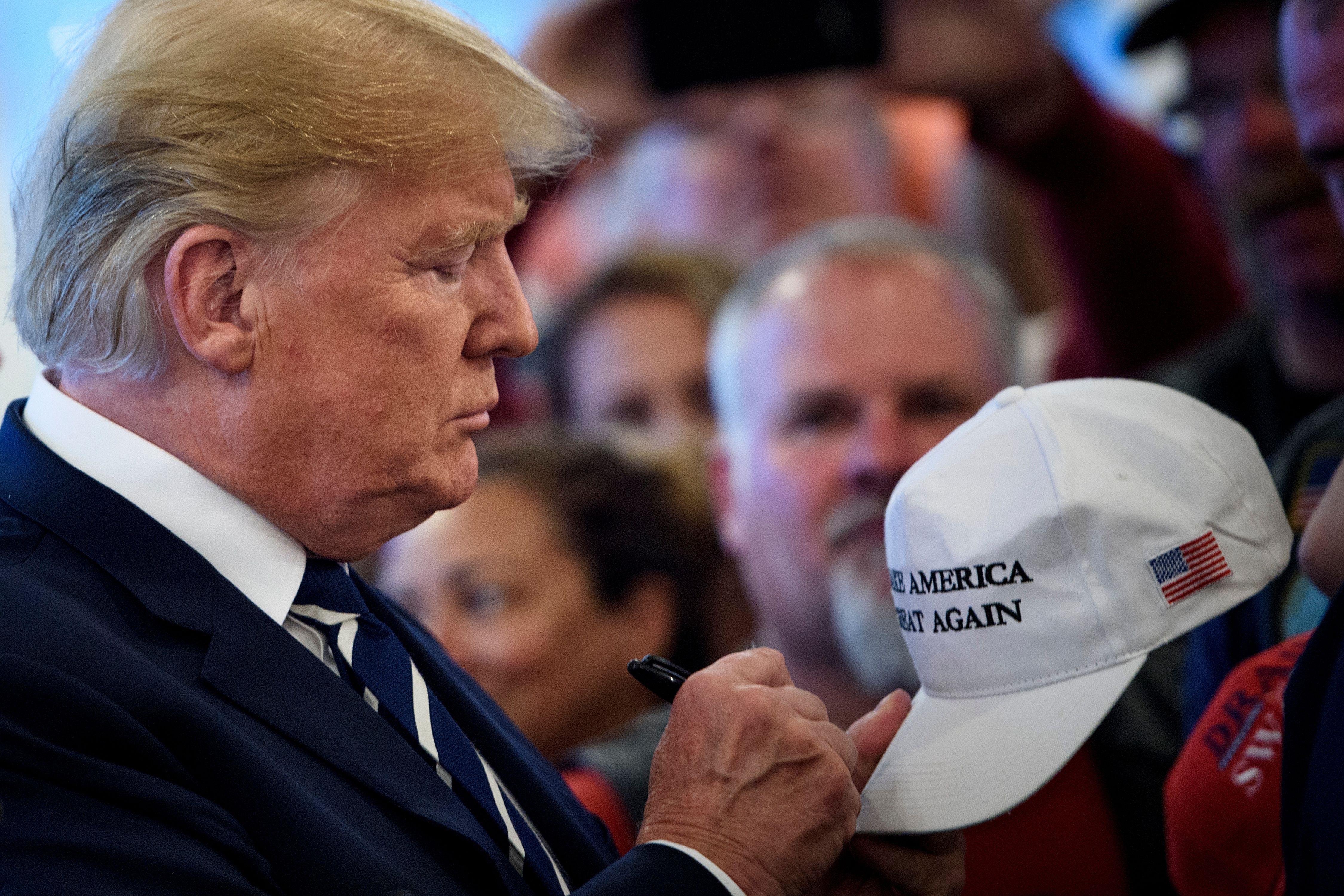President Donald Trump signs a hat while meeting with supporters during a Bikers for Trump event at the Trump National Golf Club August 11, 2018 in Bedminster, New Jersey. 
