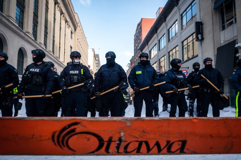 Police, standing in a snowy street in Ottawa, Ontario, look on after removing demonstrators on February 19, 2022.