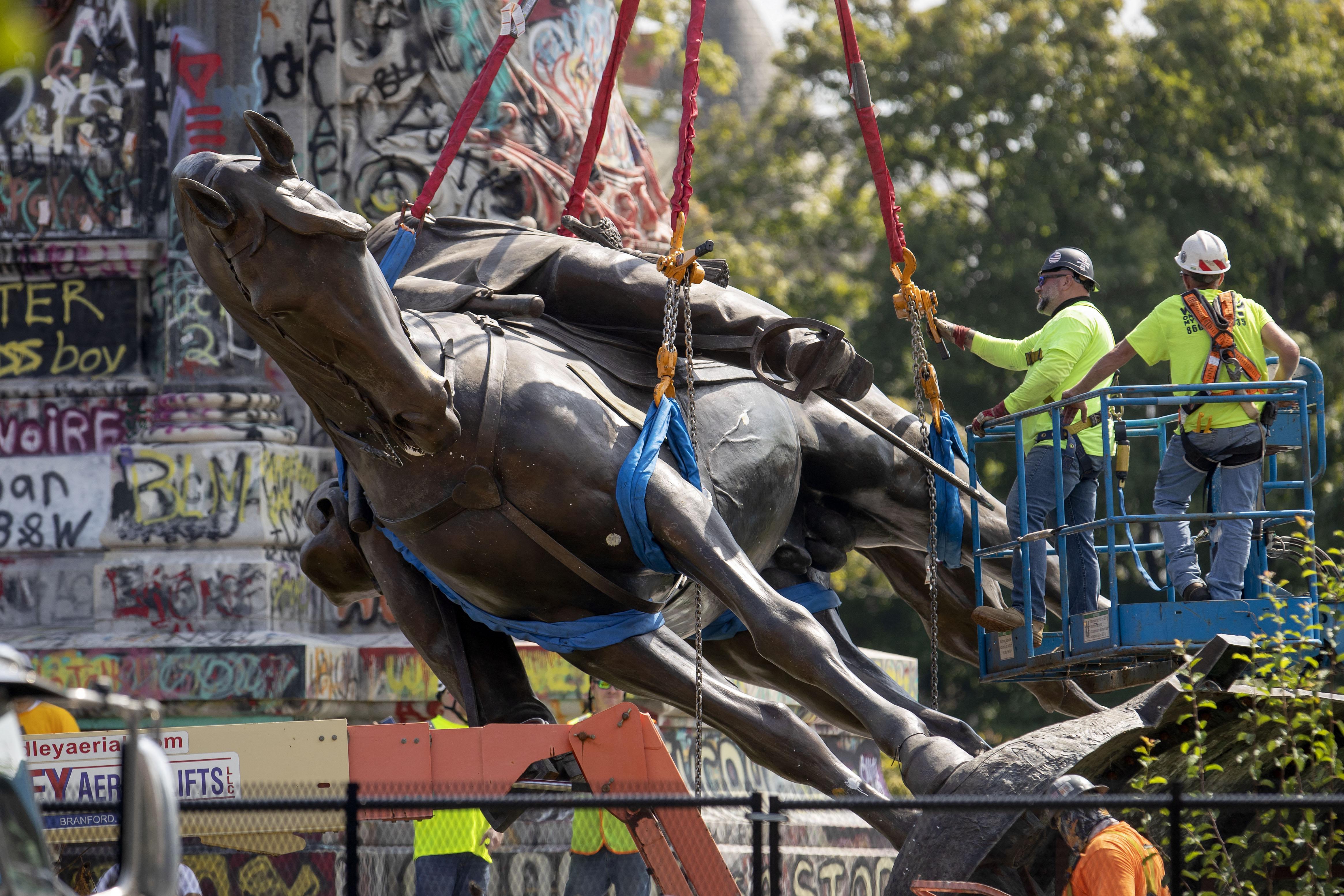 The workers on a platform lower the copper Robert E. Lee statue. 
