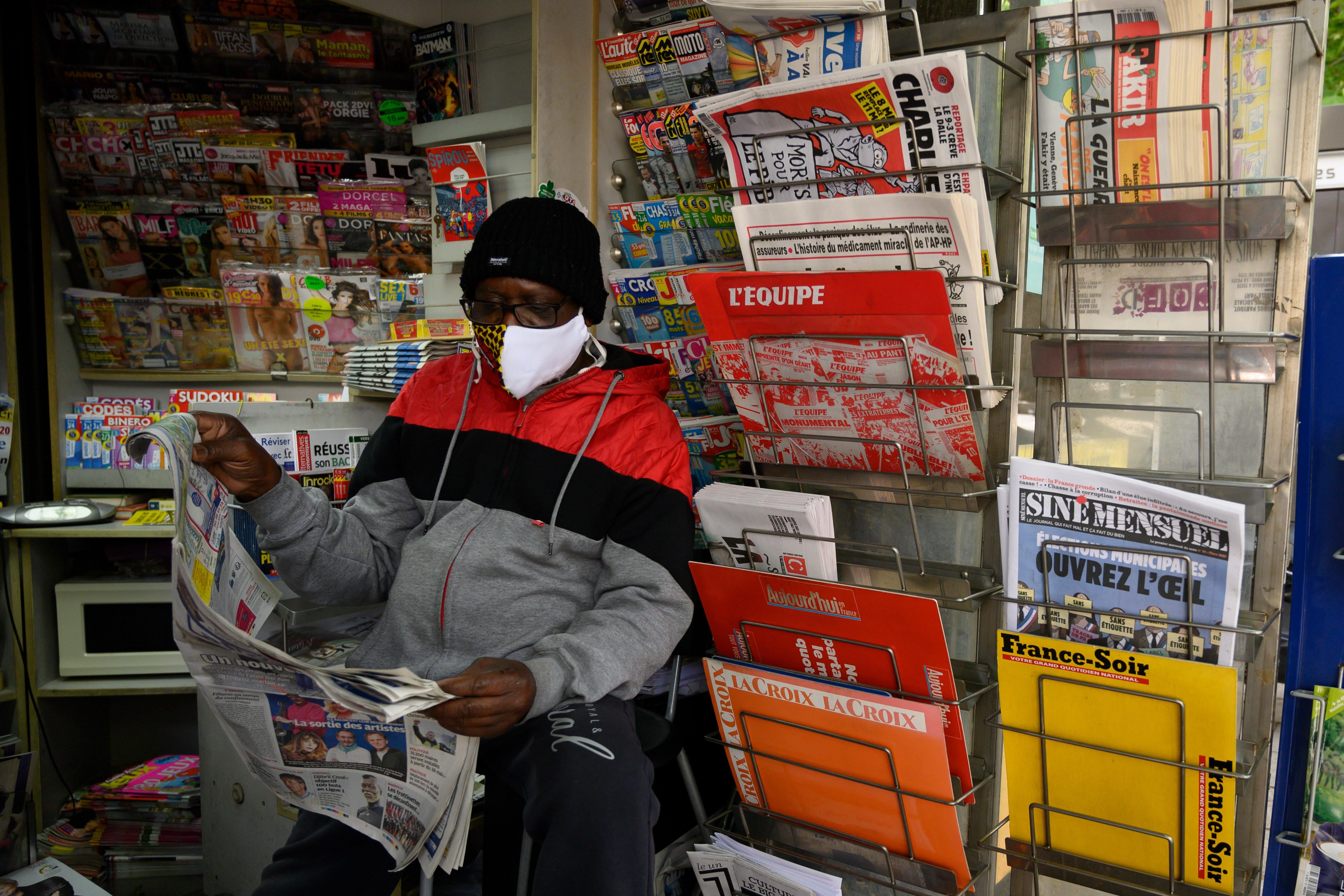 A man reading the local paper at a newsstand in France.