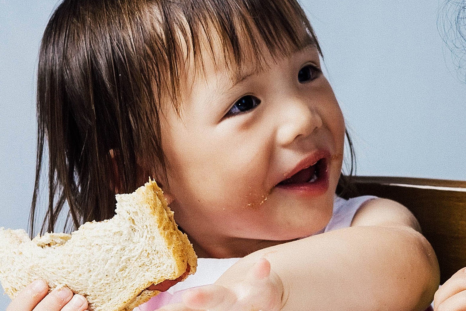 Toddler eating a peanut butter sandwich.