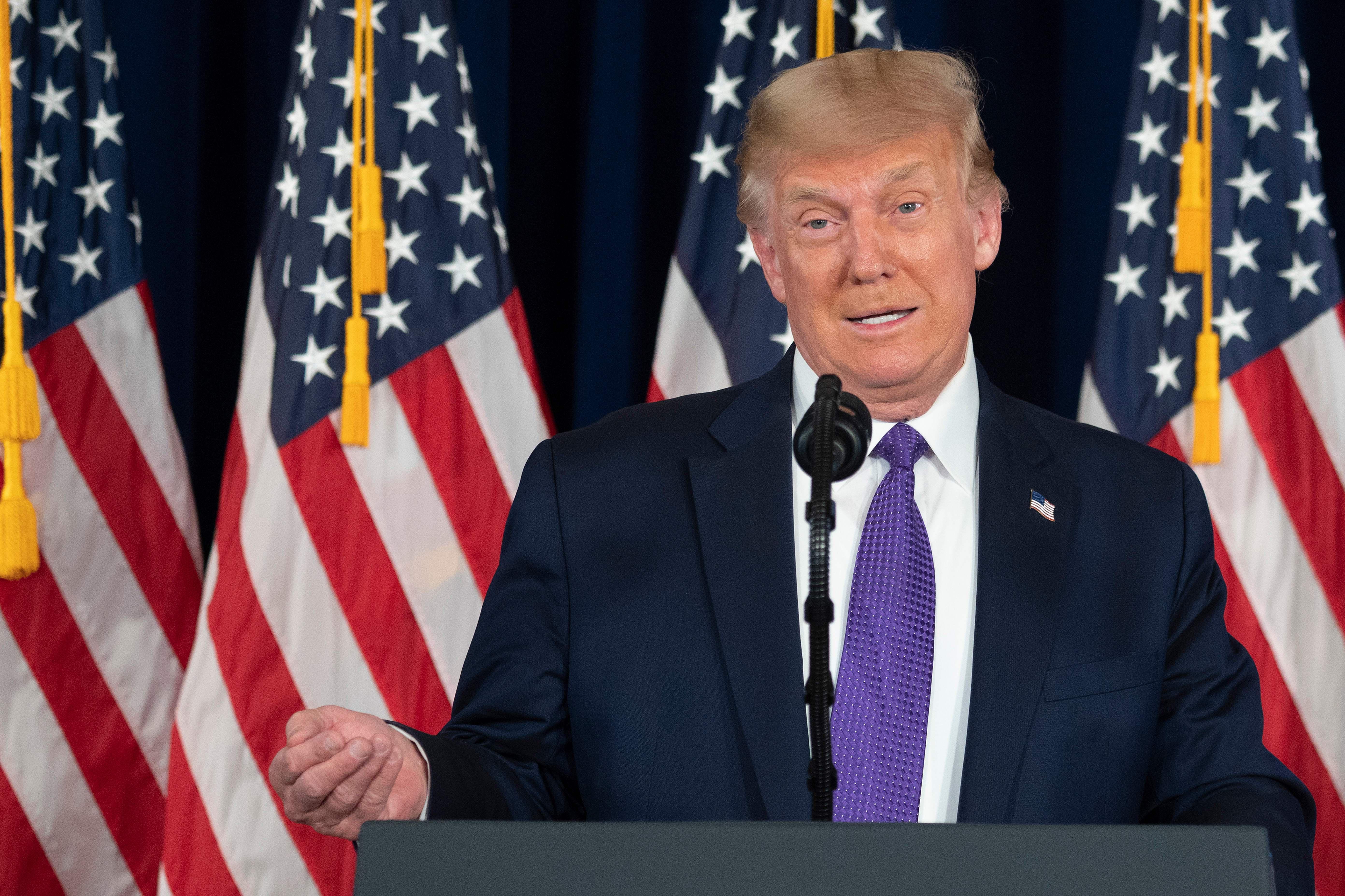 Trump speaks at a podium, with American flags behind him