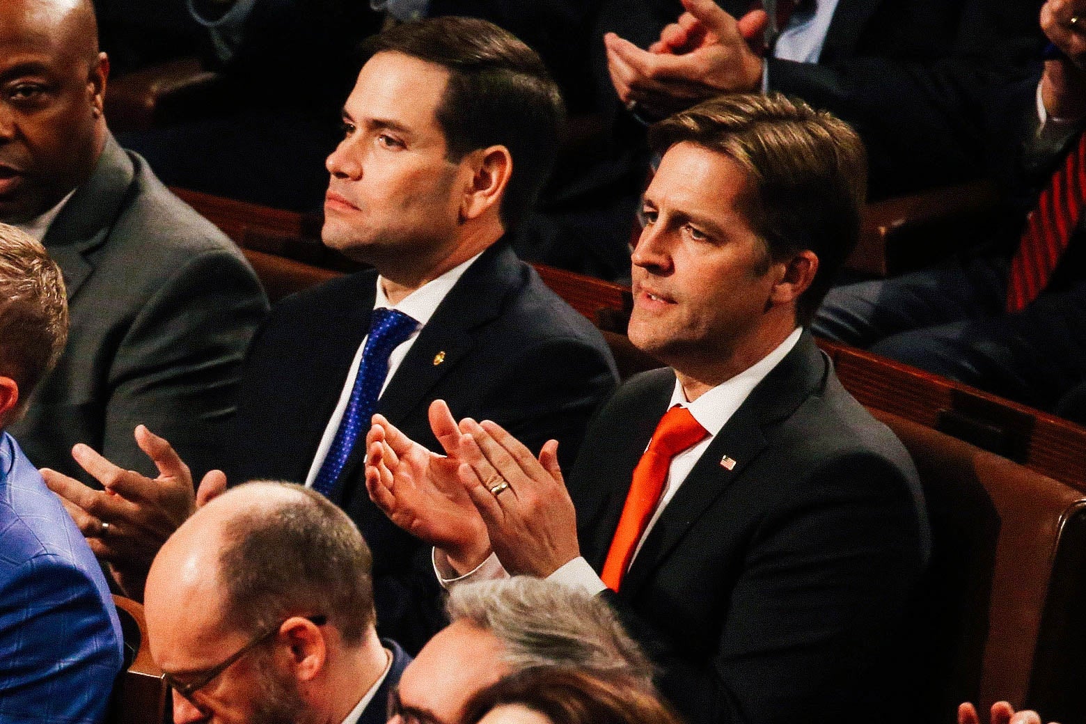 Sasse claps while seated on a bench next to Florida Sen. Marco Rubio.