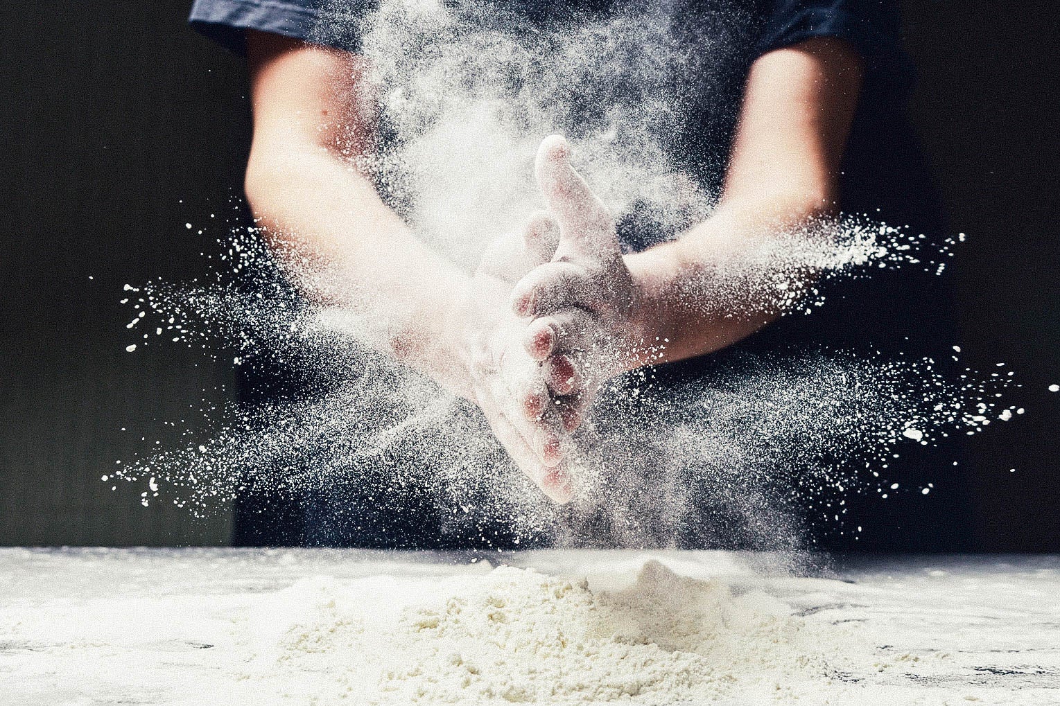Man spreading flour while making dough.
