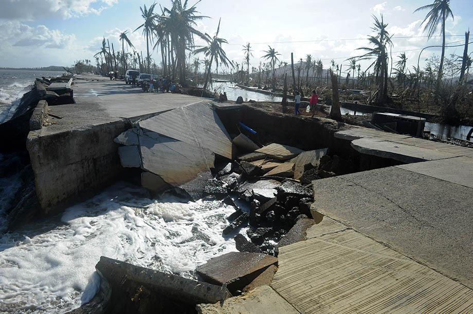 Residents cross a collapsed highway caused by the storm surge in Palo, eastern island of Leyte on November 10, 2013, three days after devastating Super Typhoon Haiyan hit the area on November 8. 