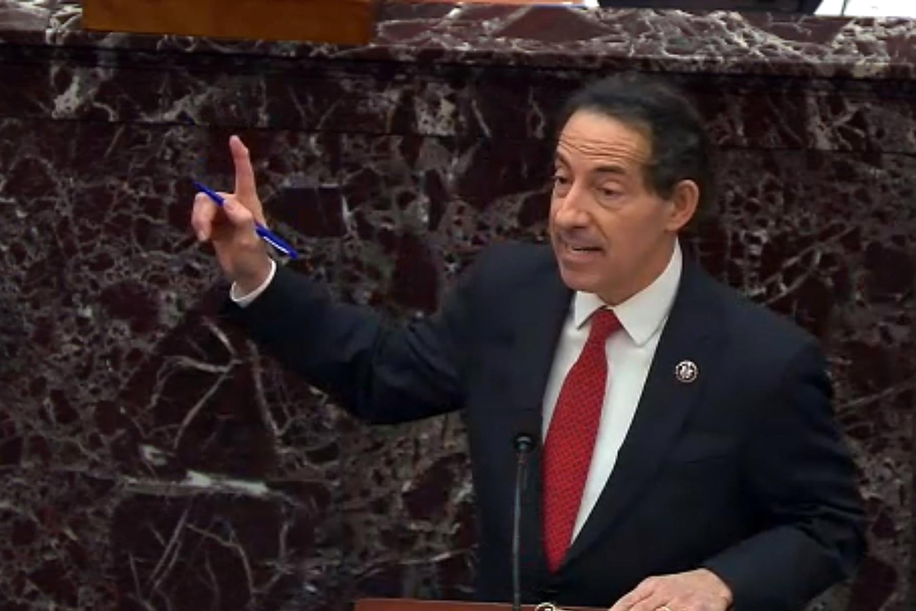 Raskin holds out his finger as he speaks at a mic