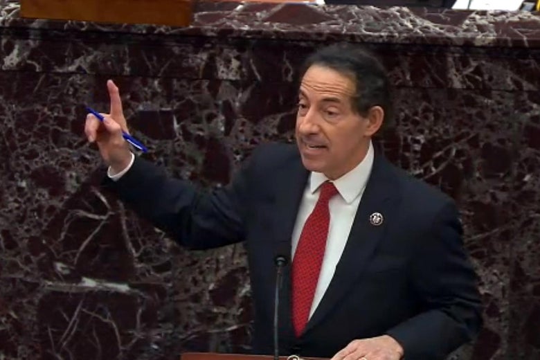 Raskin holds out his finger as he speaks at a mic