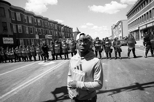 A young man stands in front of the line of police officers on North Avenue, Baltimore, April 29, 2015.