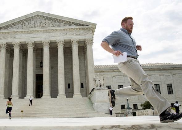 An intern runs to hand off a copy of the decision of Texas Department of Housing and Community Affairs v. Inclusive Communities Project at the Supreme Court on June 25, 2015. 