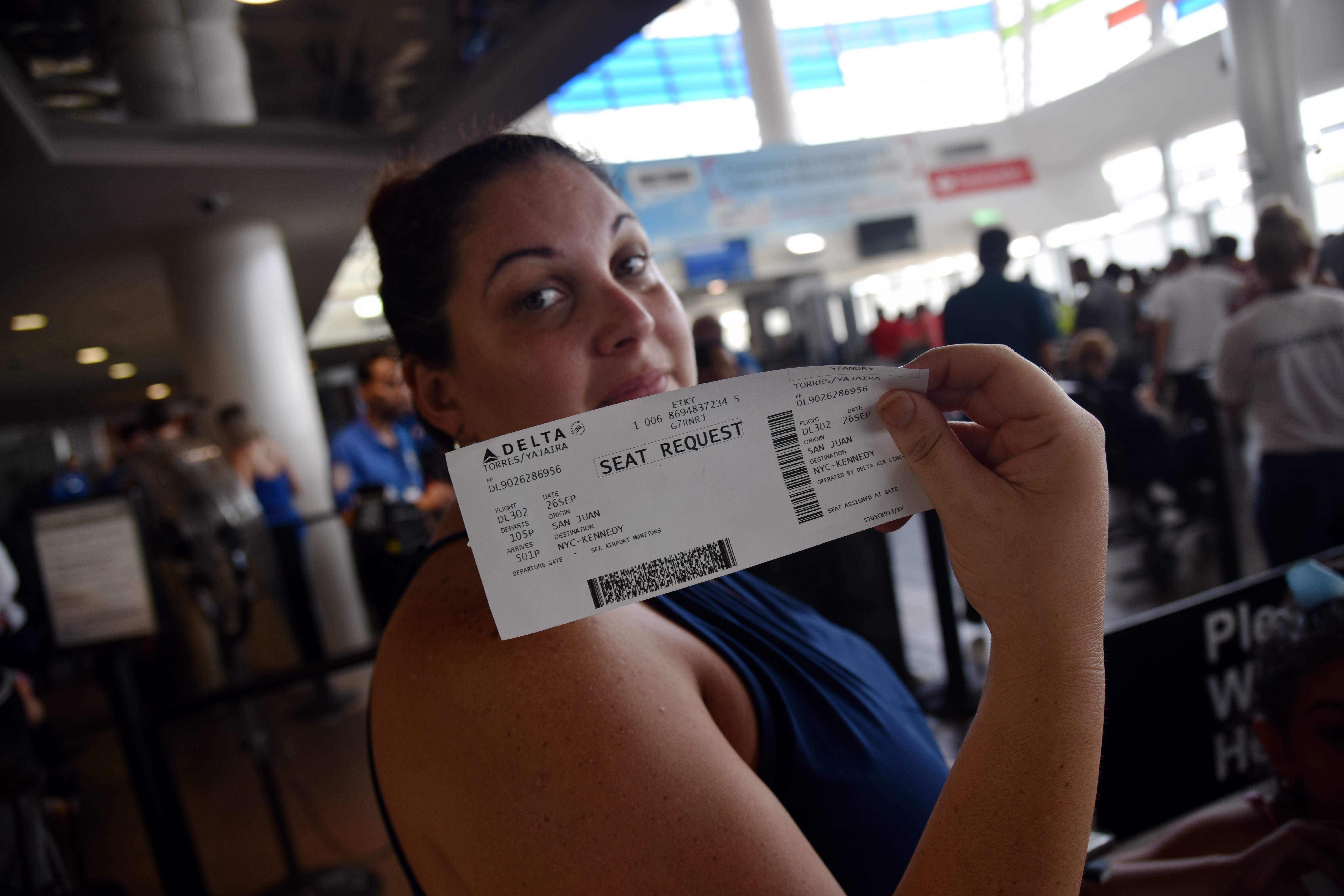 A woman shows her ticket for a seat request while waiting in a line at Luis Munoz Marin International Airport, in San Juan, Puerto Rico, on September 26, 2017, as some flights are still being rescheduled for one or two weeks. 
The US island territory, working without electricity, is struggling to dig out and clean up from its disastrous brush with the hurricane, blamed for at least 33 deaths across the Caribbean. / AFP PHOTO / HECTOR RETAMAL        (Photo credit should read HECTOR RETAMAL/AFP/Getty Images)