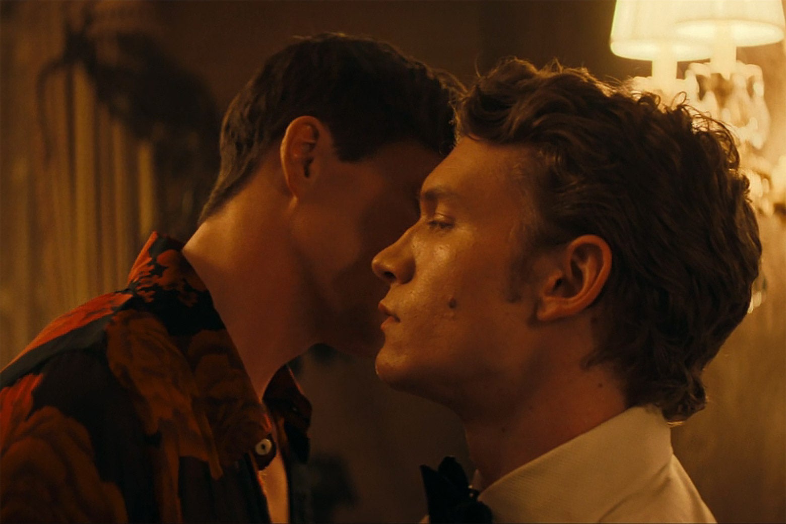 A man speaks to another man directly into his right ear.