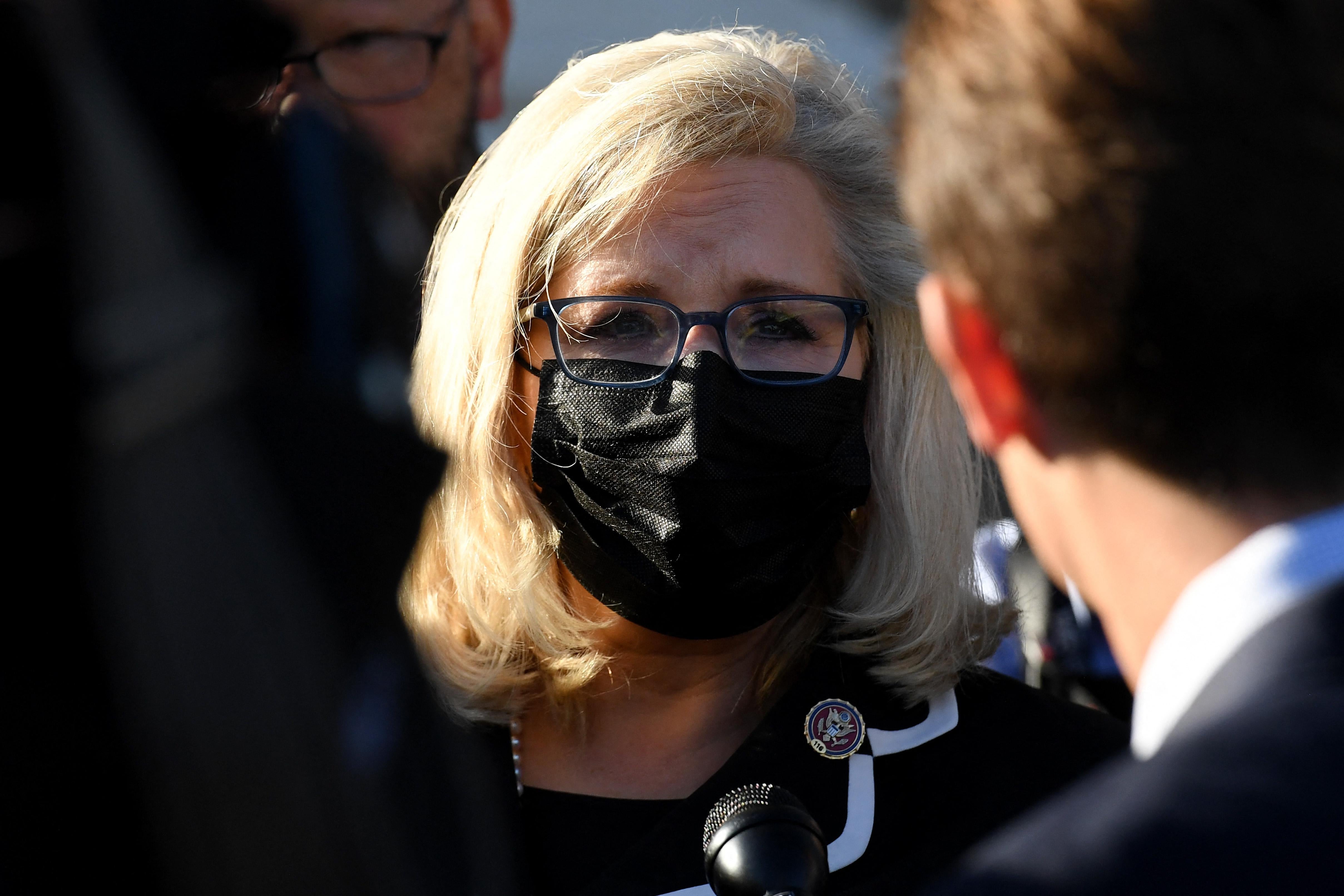 Cheney in a black mask talking to reporters outside