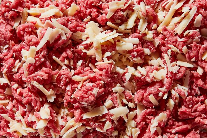 A close up of ground beef mixed with shredded cheese.