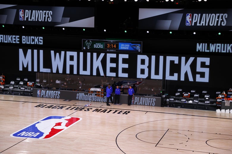 An empty basketball court with four referees off to the side.