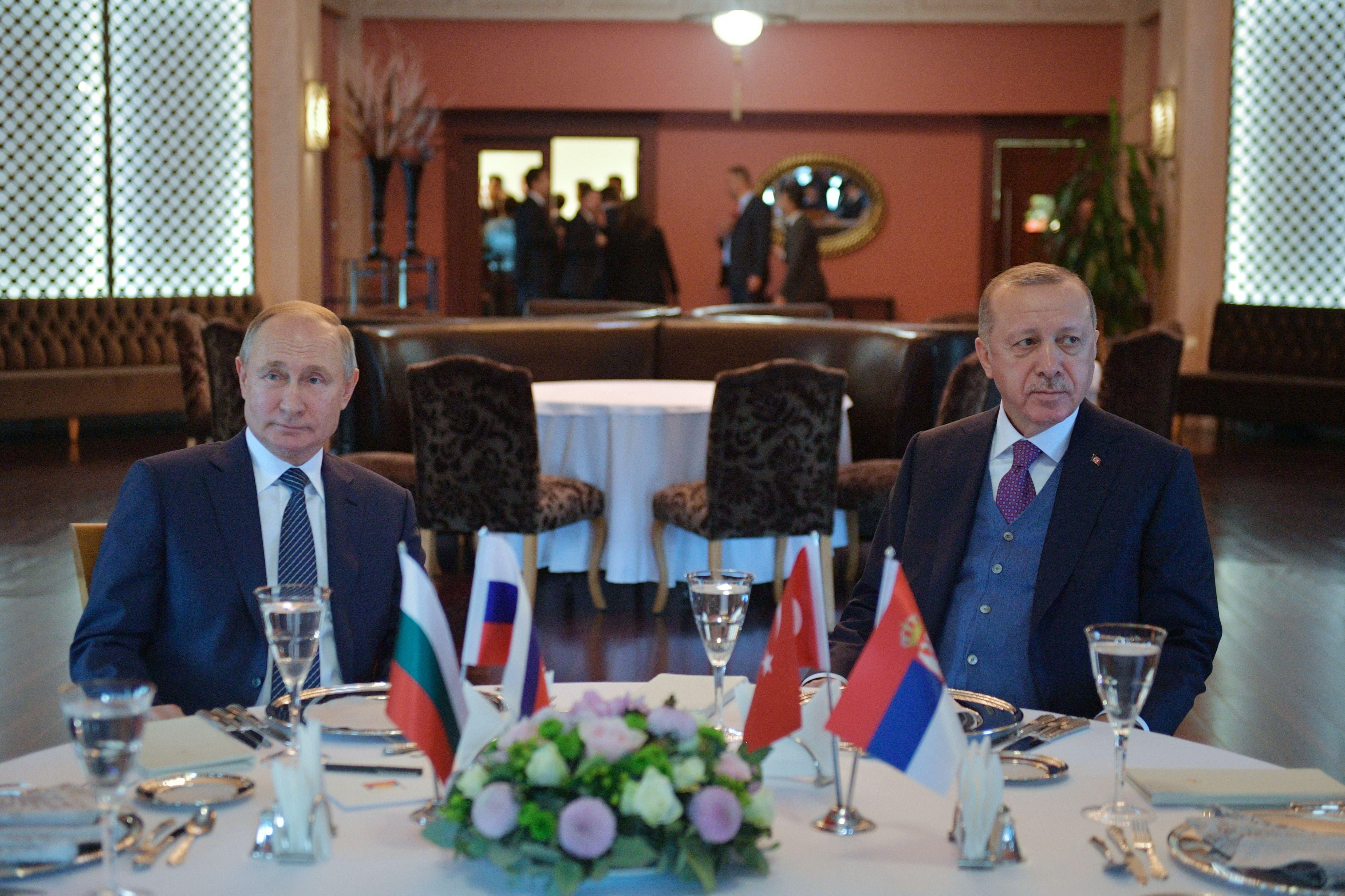 Russian President Vladimir Putin and Turkish President Recep Tayyip Erdogan sit at the same table looking away from one another during a meeting in Istanbul.