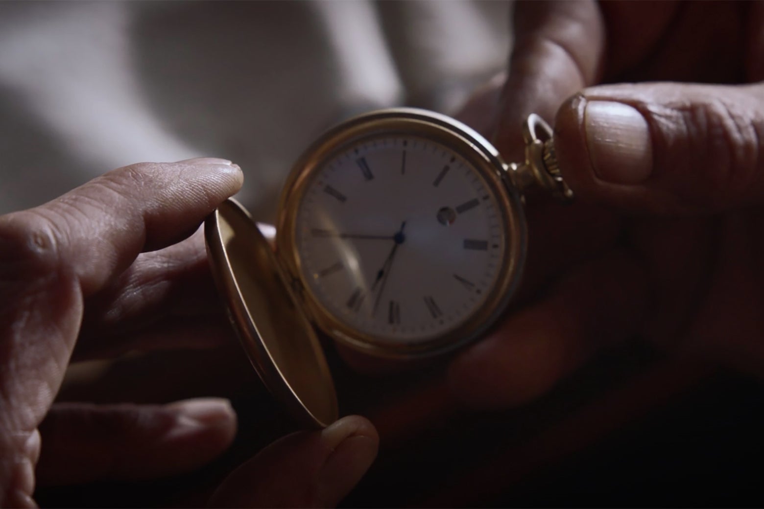 A man's hands hold a pocket watch in a still from Watchmen.