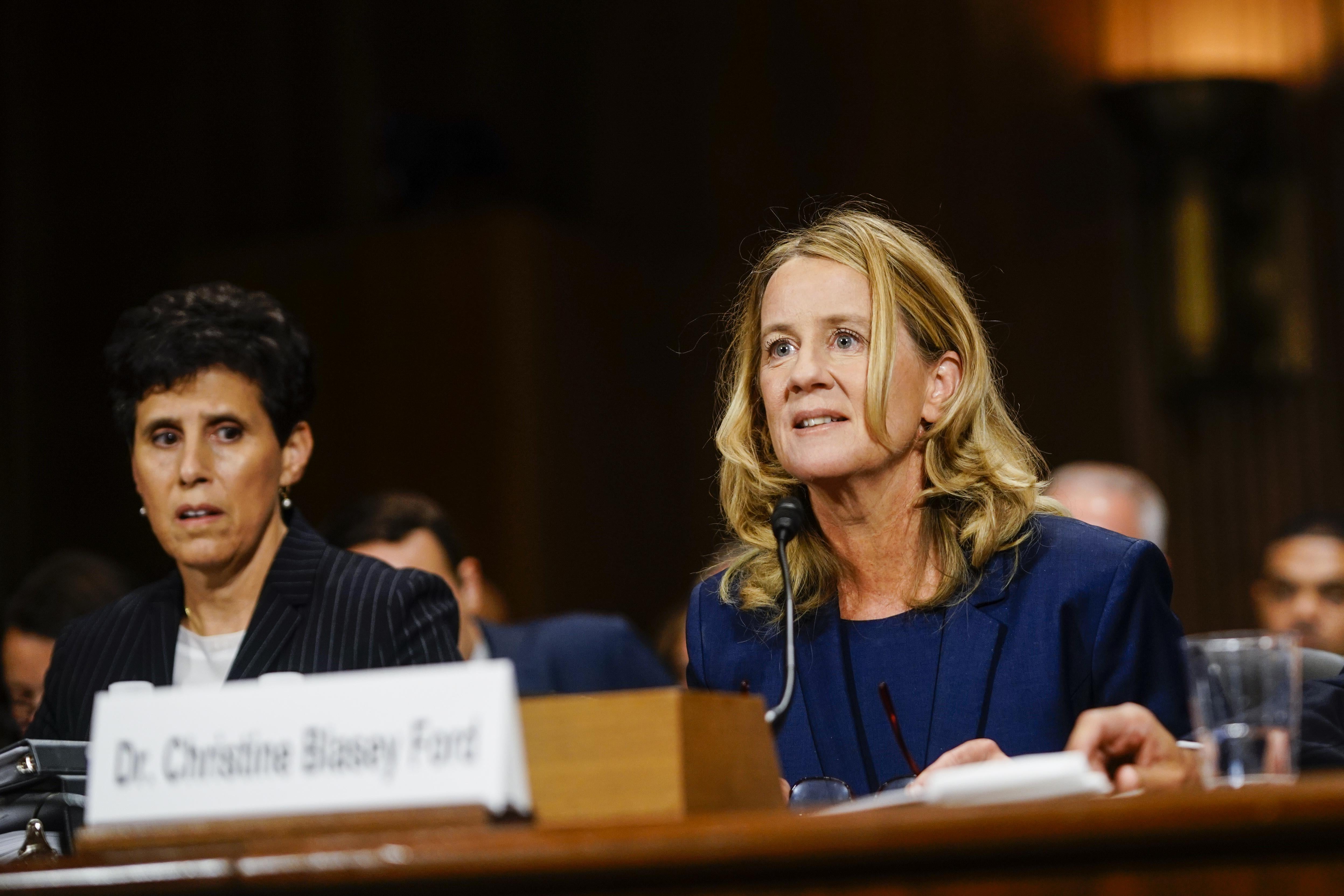 Christine Blasey Ford sits before the committee, appearing alert; her lawyer, Debra Katz, sits nearby